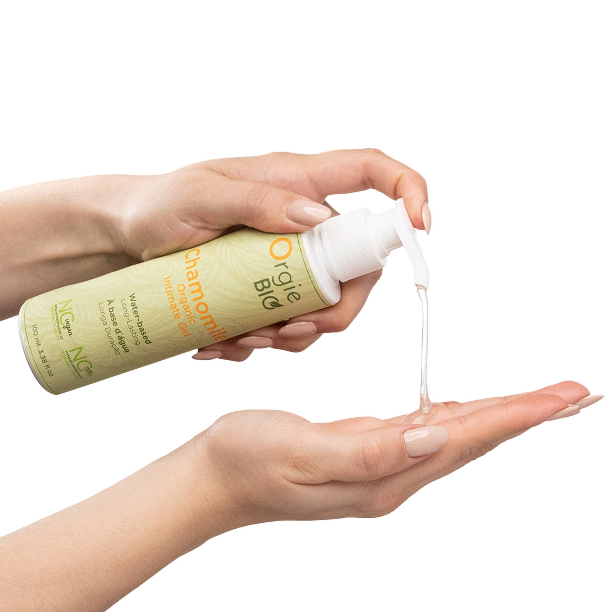 Hand holding a bottle of Orgie Bio chamomile body lotion with cream being dispensed.