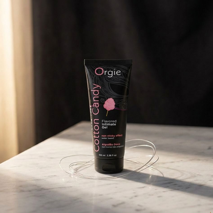 Tube of Orgie Cotton Candy flavored intimate gel on a marble surface with a dark background