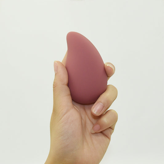 The Pebble vibrating stone massager in Dusty Rose, an organic palm-sized vibrator made of smooth matte silicone.