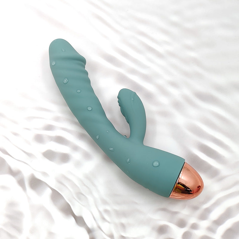 The Crescent luxury rabbit vibrator by Sigh . . . in Light Sage green. A dual-action silicone vibrator with a curved internal arm and external clitoral stimulator, displayed on a neutral background."