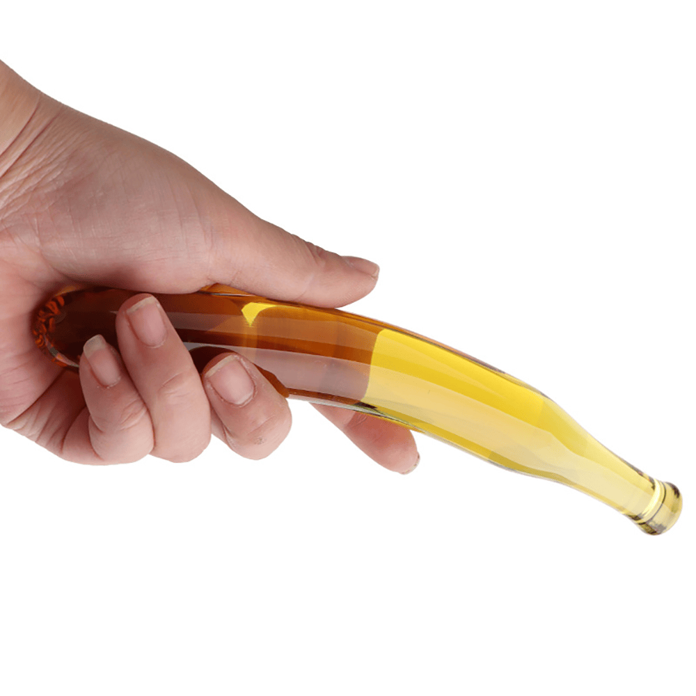Hand holding a transparent bottle with a gold cap against a white background